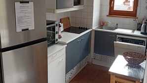 A compact kitchen with a refrigerator, stove, sink, and a window with a view. - Apartment at the foot of the slopes, near outdoor swimming pool (summer) with garage. (Saint-François-Longchamp)