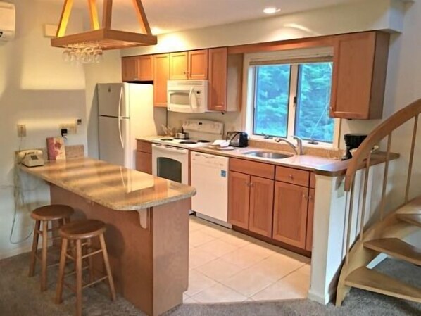 A kitchen with wooden cabinets, a built-in oven, a microwave, and a window.