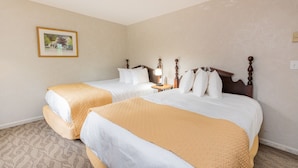 Habitación de hotel con dos camas, una mesita de noche con lámpara y un cuadro en la pared.