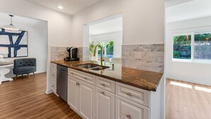 A modern kitchen with white cabinetry, a granite countertop, and a built-in dishwasher.