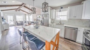 Una cocina moderna con armarios blancos, una isla de mármol y un refrigerador de acero inoxidable.