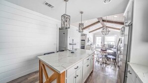 Una cocina con una isla de mármol, armarios de madera y luces colgantes.