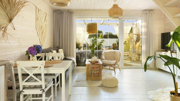 Amplia sala de estar con techo de madera, muebles blancos y grandes ventanales con vistas al exterior.