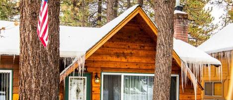 A cabin with a green door, a window, and a chimney.