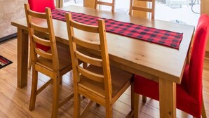Un coin repas en bois avec une grande table, plusieurs chaises et un coussin rouge.