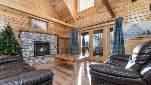 A cozy cabin interior with a stone fireplace, leather furniture, and a Christmas tree. - Indulge in the Perfect Family Adventure (Sugarloaf)