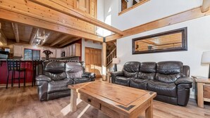 A spacious living area with a wooden coffee table, leather sofas, and a kitchen in the background. - Indulge in the Perfect Family Adventure (Sugarloaf)