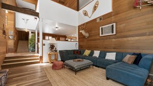 A modern living room with a sectional sofa, a small rug, and wooden walls. - The Circle Moon - 1 mi to Bear Mtn/ Game Room+Spa! (Big Bear Lake)