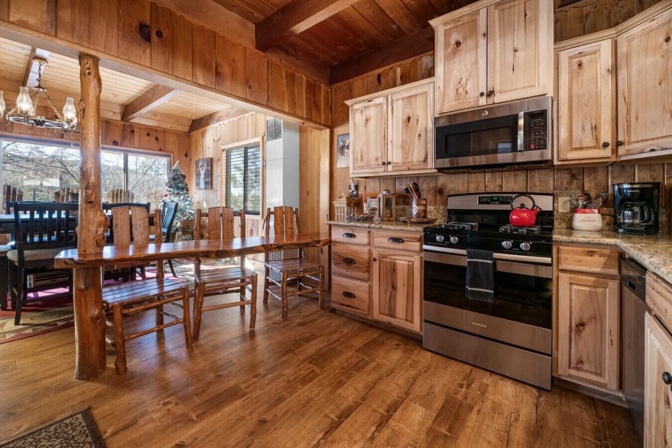A wooden kitchen with a large dining table, cabinets, a stove, and a microwave.