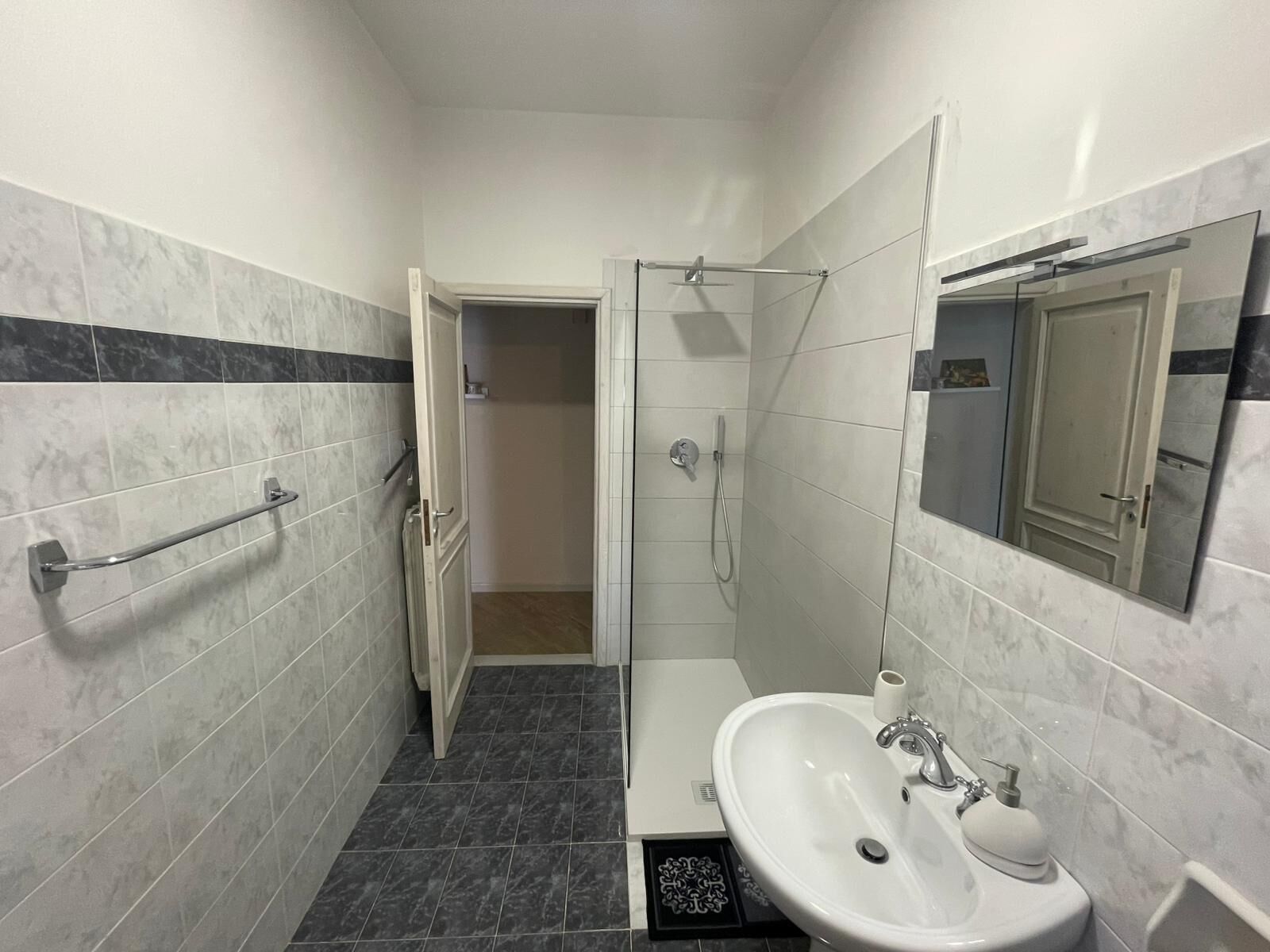 Un baño con lavamanos blanco, espejo y ducha.