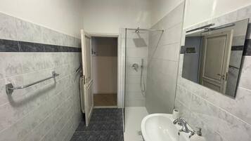 Un baño con lavamanos blanco, espejo y ducha.