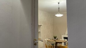 A white door with a glass panel, leading to a room with a dining table, chairs, and a hanging light fixture. - Goti Rooms B&B (Sant'Agata de'Goti)