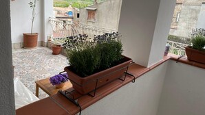 A balcony with potted plants, a wooden table, and a view of a mountainous landscape. - Goti Rooms B&B (Sant'Agata de'Goti)