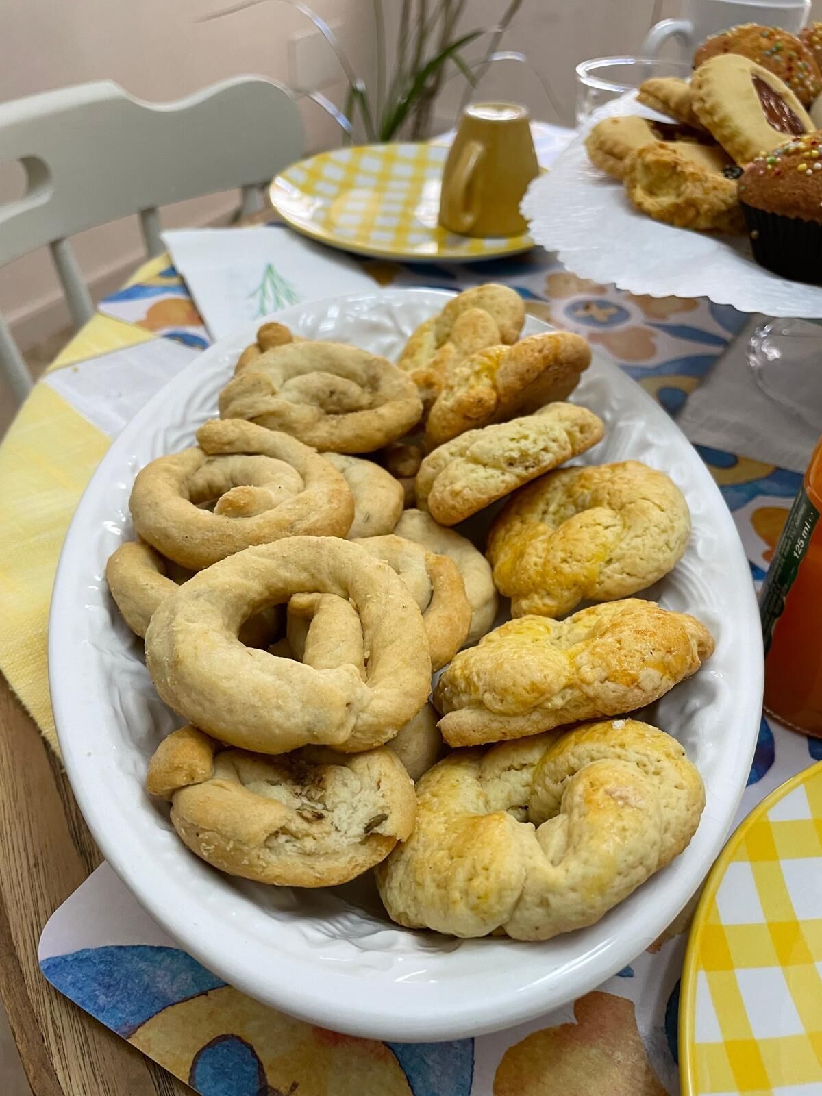 Une assiette remplie de diverses pâtisseries est posée sur une table recouverte d’une nappe à carreaux.