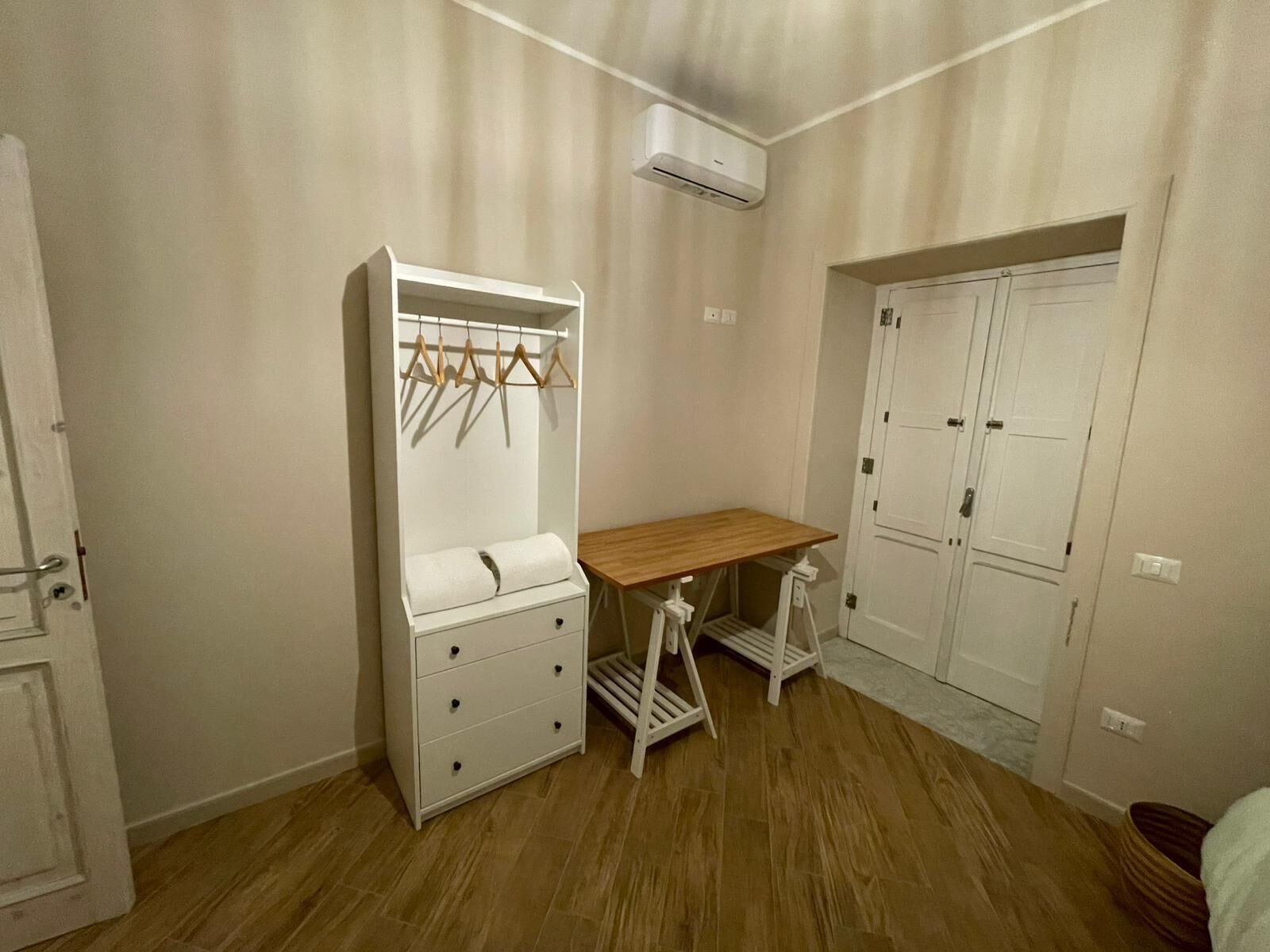 Ein Schlafzimmer mit Einbauschrank, Holztisch und Kleiderstange.