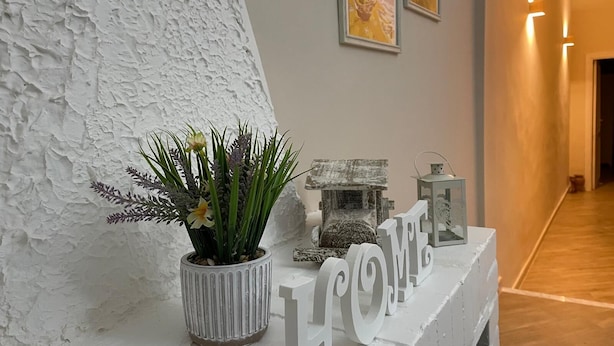 A reception desk with a potted plant, a decorative lantern, and a 'HOME' sign. - Goti Rooms B&B (Sant'Agata de'Goti)