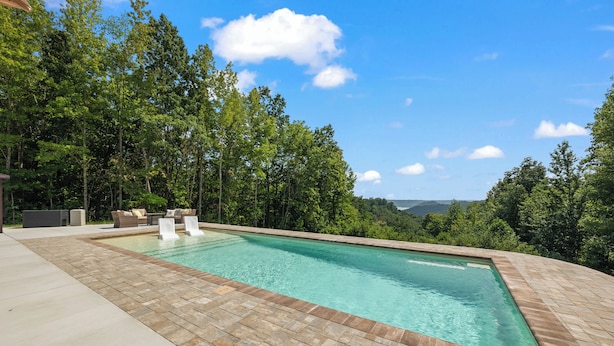 A rectangular swimming pool with a tiled edge, surrounded by a paved deck.