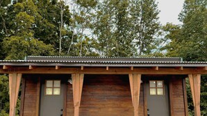 A wooden cabin with two doors, a metal roof, and a brick floor.