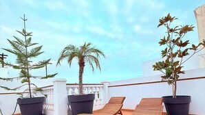 A rooftop terrace with two wooden lounge chairs, a palm tree, and two potted plants. - Centric but quiet. Terrace with views to the sea (Nerja)
