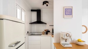 A compact kitchen with white cabinetry, a black range hood, a vintage coffee machine, and a framed artwork on the wall. - Centric but quiet. Terrace with views to the sea (Nerja)