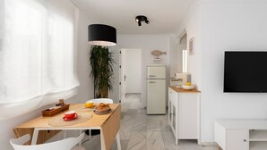 A modern kitchen with a dining area, white cabinetry, a refrigerator, and a flat-screen TV. - Centric but quiet. Terrace with views to the sea (Nerja)