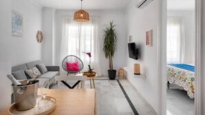 A modern living room with a sofa, a chair, a dining table, a TV, and a potted plant. - Main street free parking 5 minutes away (Nerja)
