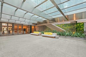 A spacious lobby with a high ceiling, a staircase, and seating areas.