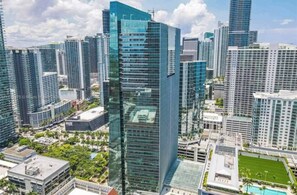 A high-rise urban area with modern skyscrapers, a central building with a glass facade, and surrounding greenery.