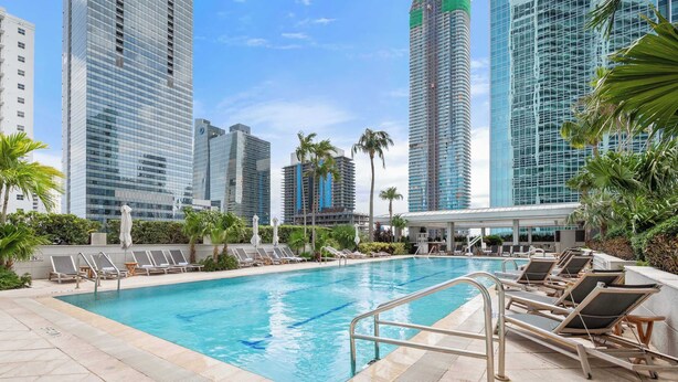 A swimming pool with lounge chairs, surrounded by tall buildings and palm trees. - Brickell Arch City Views Pool & Free Parking (Miami)