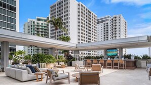 A rooftop lounge with outdoor seating, a bar area, and a TV screen. - Brickell Arch City Views Pool & Free Parking (Miami)