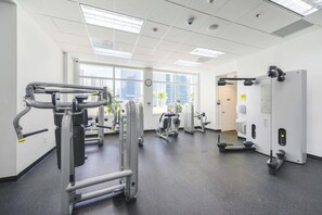 A gym with various exercise machines, large windows, and a clean, modern design.