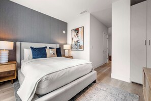 A modern bedroom with a large bed, bedside tables, a painting, and a wardrobe. - Smart Brickell Balcony Pool & Gym (Miami)