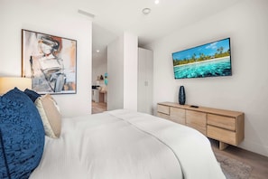 A bedroom with a bed, a TV, a painting, and a wooden dresser. - Smart Brickell Balcony Pool & Gym (Miami)