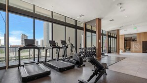 Une salle de sport moderne équipée de tapis de course, de vélos elliptiques et de bancs de musculation.