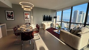 Een moderne woonkamer met een eethoek, grote ramen met uitzicht over de stad en moderne meubels.