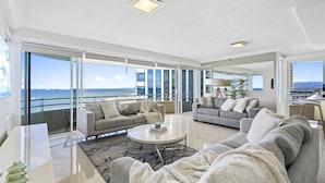 A spacious living area with large windows, a balcony, and a view of the ocean.