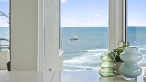 A view of the ocean through a window, with a ship in the distance.