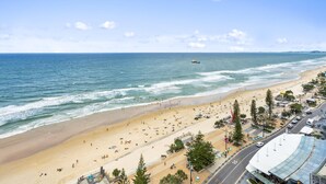 A beach with a sandy shore, a boat in the water, and a road with a speed limit sign. - Spacious 2 Bedroom Ocean View Apartment - Q Stay (Surfers Paradise)