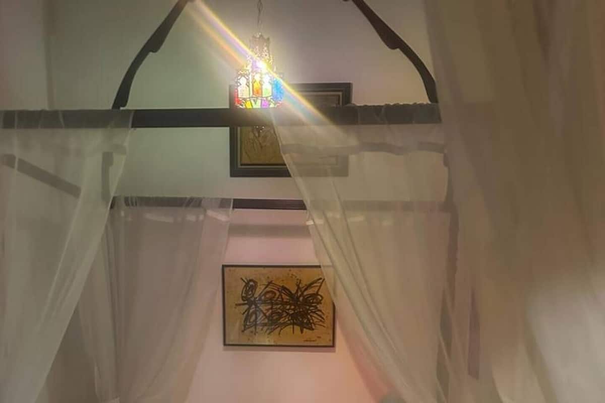 Un letto a baldacchino, un tavolino e una lampada fissata al muro.