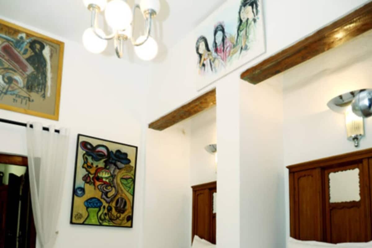 Una camera d'albergo con due letti, un lampadario e opere d'arte alle pareti.