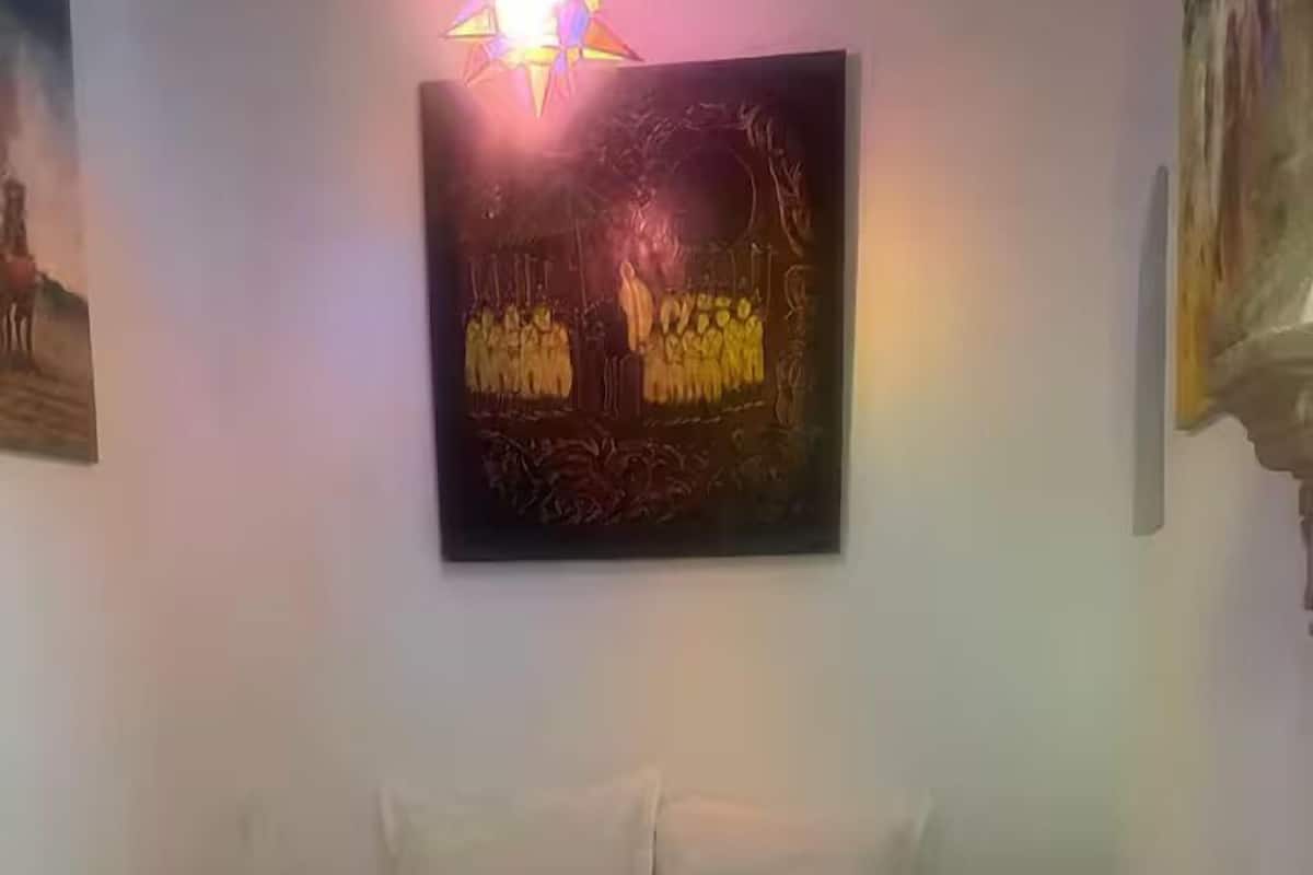 Un letto rifatto con asciugamani arrotolati, un lampadario a forma di stella e un quadro appeso al muro.
