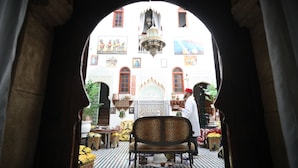 Een traditioneel Marokkaans interieur met een centrale fontein, versierde decoratie en een uitzicht door een boog.