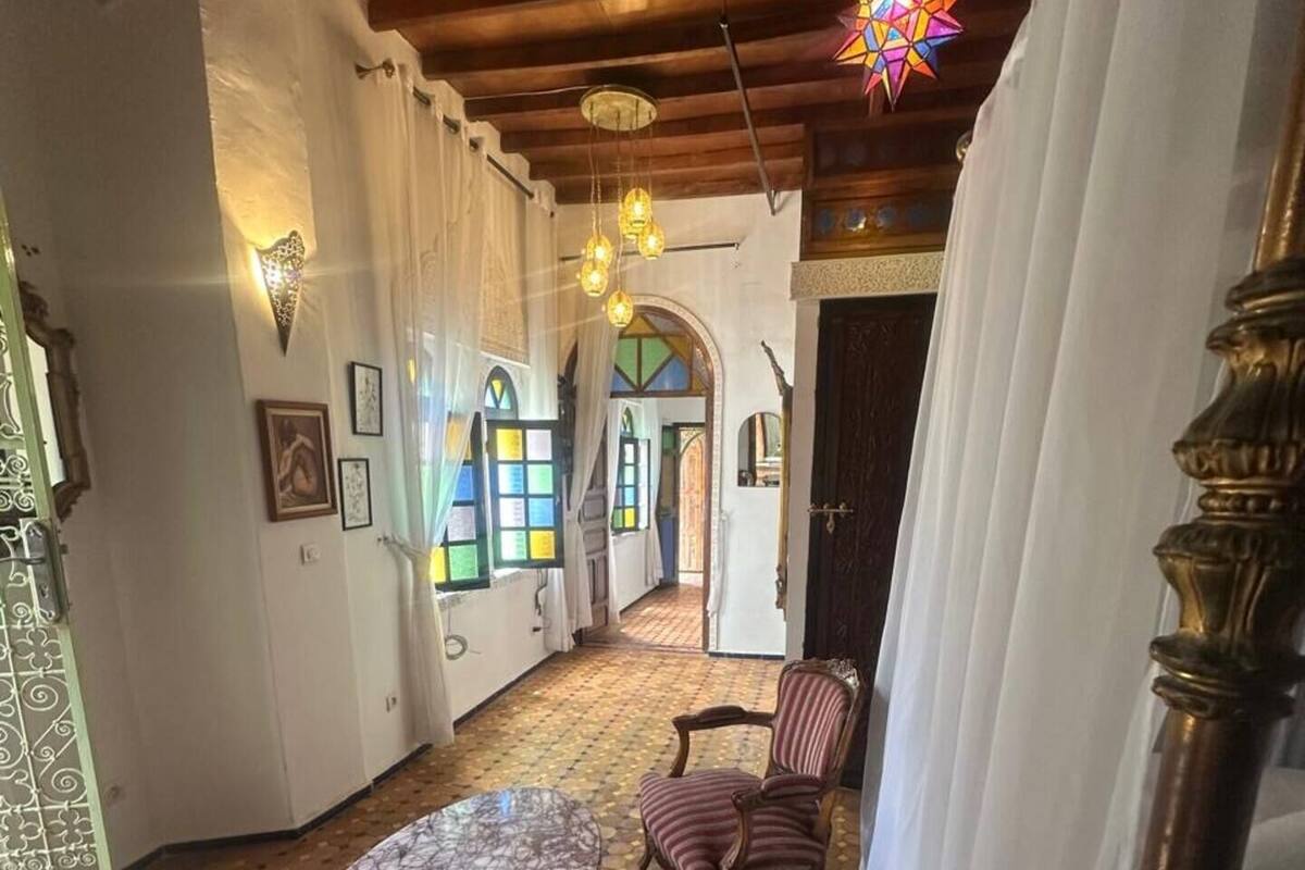 Una stanza con pavimento a motivi, un tavolo rotondo, due sedie a righe e un lampadario decorativo a forma di stella.