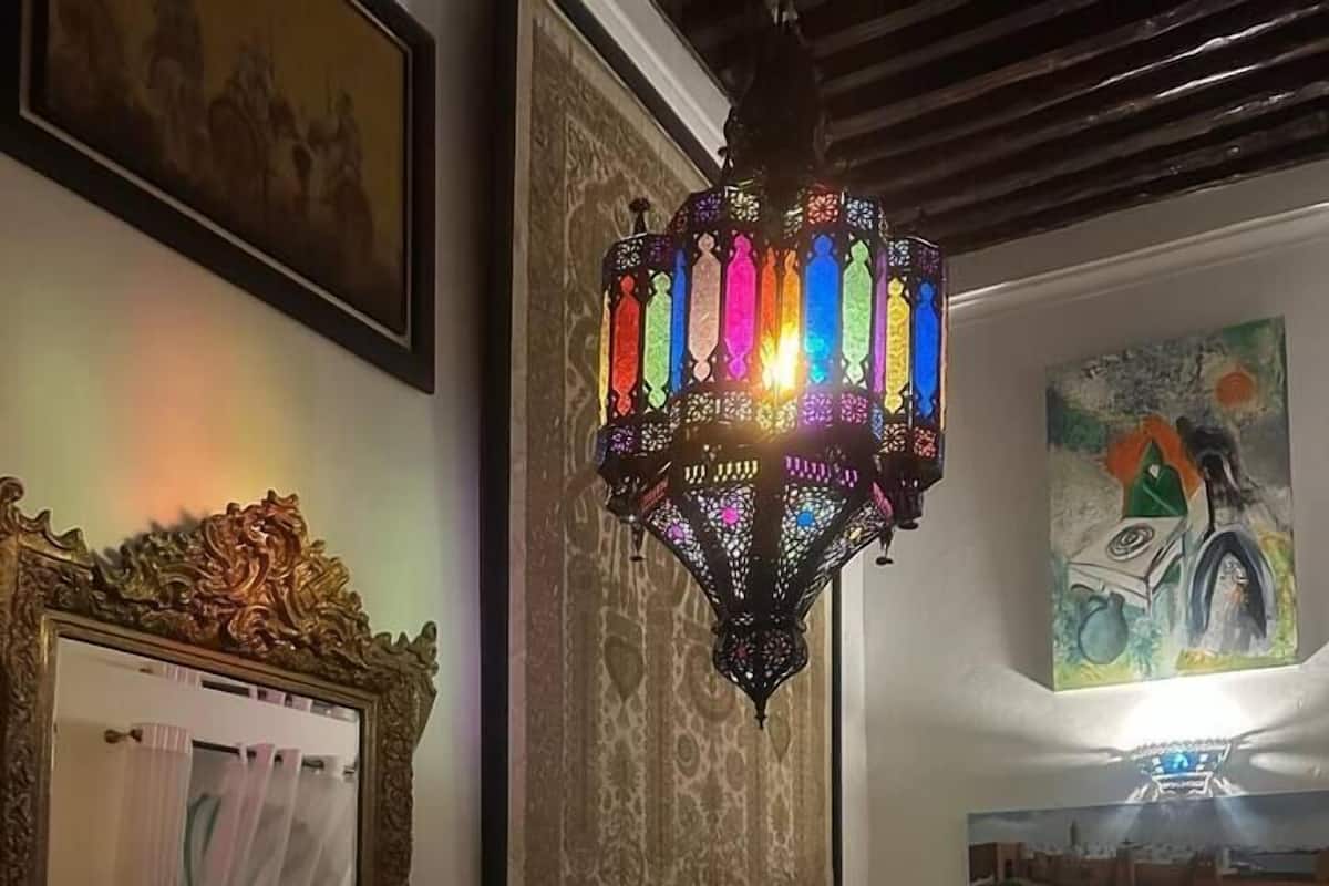 Una camera da letto con un letto, un lampadario, un arazzo incorniciato e un quadro appeso al muro.