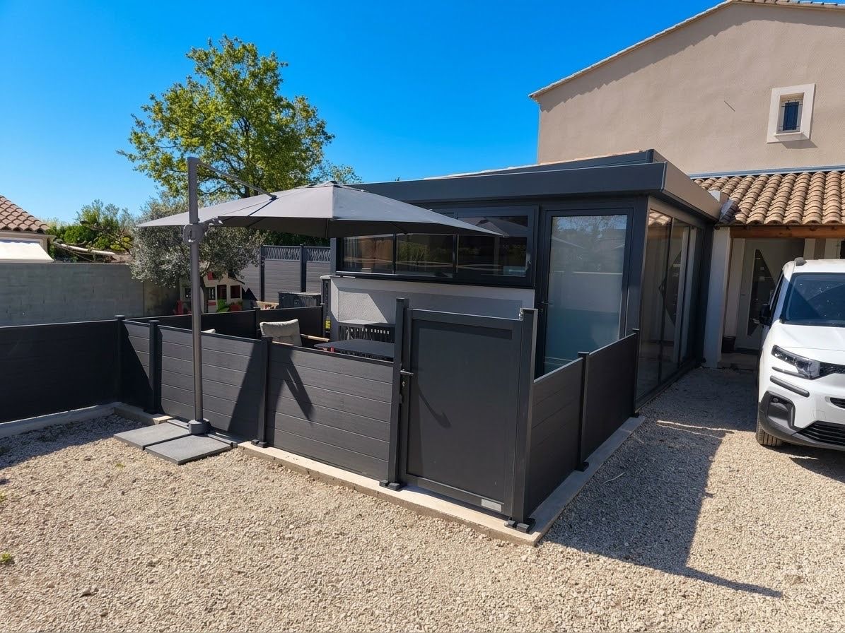 Un espace extérieur moderne, aménagé pour se détendre, avec un patio couvert, une zone délimitée par une clôture et un véhicule garé à proximité.