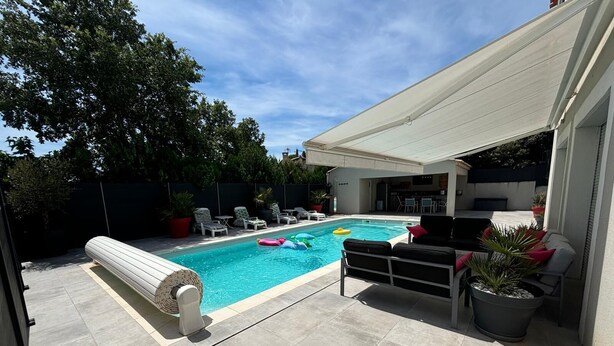 A backyard with a swimming pool, lounge chairs, and a covered patio area. - Charming Independent Studio (La Motte-d'Aigues)