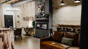 Een moderne woonkamer met een bruine leren bank, een eettafel en een open haard.