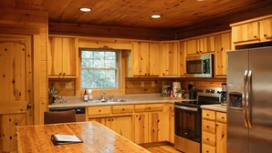 Una cucina in stile baita con elementi in legno, un'isola centrale, elettrodomestici integrati e una finestra che garantisce luce naturale.
