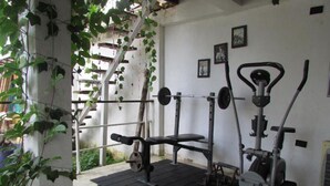A gym with a bench press, barbell, and weight plates. - JUMANJI  (Palomino)