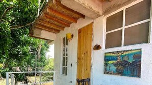 A rustic outdoor seating area with a wooden table and chairs, a thatched roof, and a painting on the wall. - JUMANJI  (Palomino)